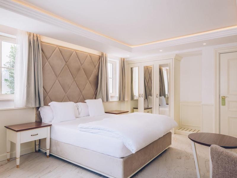 Brightly furnished hotel room with double bed, nightstand, and seating area.