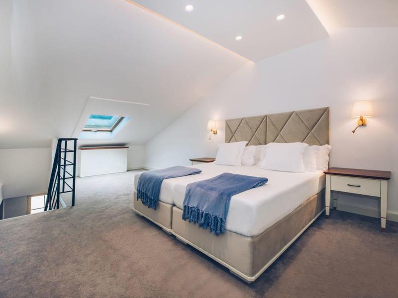 Modern bedroom with double bed, blue throws, and skylight in a hotel room.