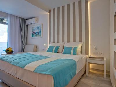 Camera d'hotel moderna con letto grande, accenti turchesi e accesso a un balcone.