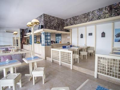 Helles, modernes Restaurant mit weißen Tischen und Stühlen sowie dekorativer Wandgestaltung.