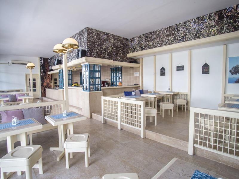 Helles, modernes Restaurant mit weißen Tischen und Stühlen sowie dekorativer Wandgestaltung.