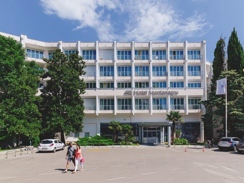 Ein modernes mehrstöckiges Gebäude mit vielen Fenstern und Bäumen links und rechts davor.