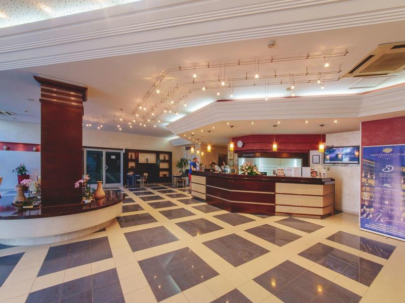 Große Hotellobby mit Empfangstresen, Sitzbereich, Marmorboden und heller Deckenbeleuchtung.