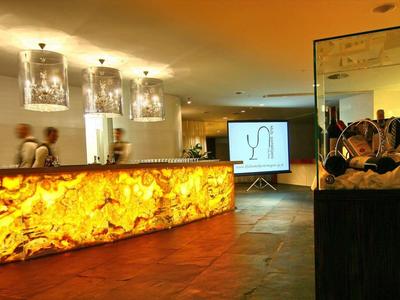 Moderne Hotellobby mit beleuchtetem Empfangstresen aus Bernstein und dunklem Marmordetail.