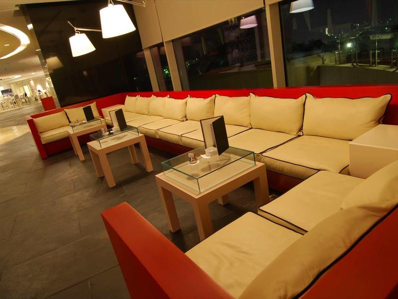 Moderner Lounge-Bereich mit roten und beigen Sofas und kleinen weißen Tischen in gemütlichem Raum.