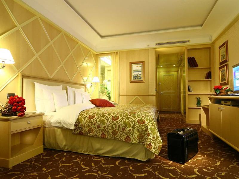 Gemütliches Hotelzimmer mit Doppelbett, Nachttischen, Teppich und TV an der Wand.