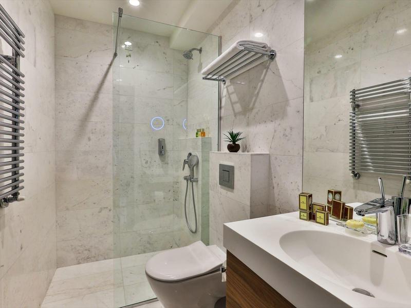 Moderner weiß-grauer Badezimmer mit Dusche, Toilette, Waschbecken und Heizkörper.