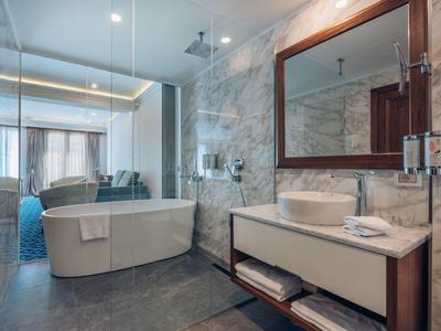 Moderne Hotelbadezimmer mit freistehender Badewanne, Waschbecken und großem Spiegel.