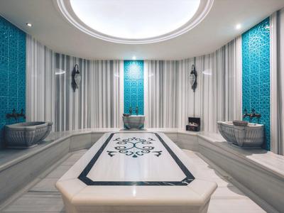 Helle, elegante türkische Badehaus-Sauna mit Marmorwaschbecken und blauen Wandakzenten.
