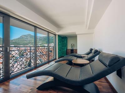 Lounge mit schwarzen Liegen und Panoramafenstern mit Blick auf Berge und Stadt.