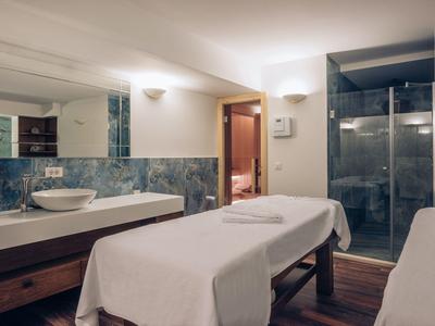 Modern eingerichteter Wellnessraum mit Massageliegen und Duschkabine