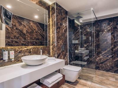 Elegantes Badezimmer mit dunklen Marmorwänden, freistehender Waschschale und ebenerdiger Dusche.