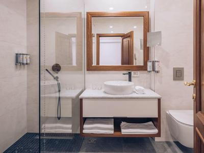 Modernes Badezimmer mit Waschbecken, Spiegel, Haartrockner und Glasdusche.