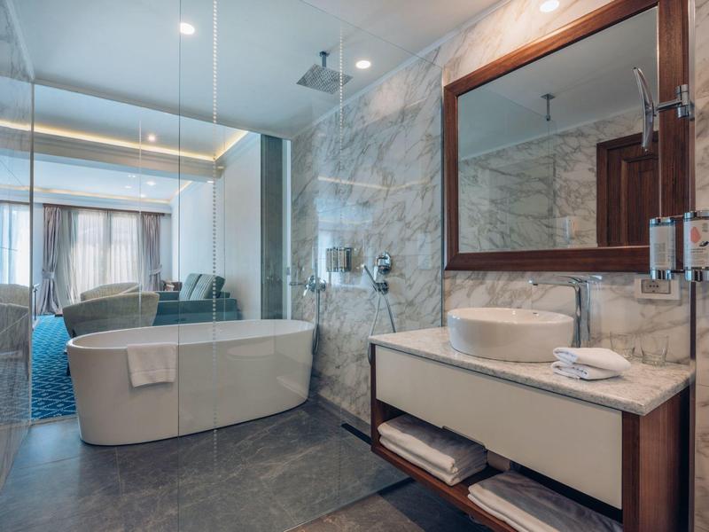 Moderne Hotelbadezimmer mit freistehender Badewanne, Waschbecken und großem Spiegel.