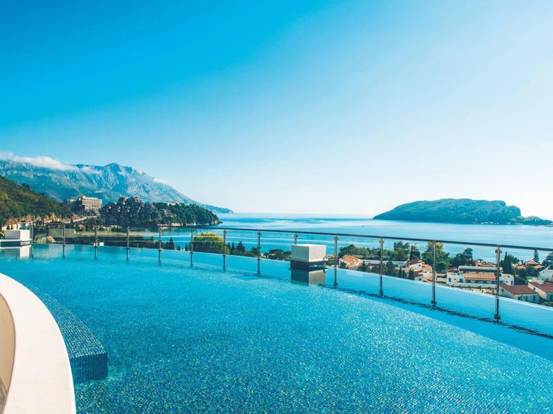 Überdachte Terrasse mit Tischen und Stühlen mit Blick auf bewaldete Hügel.