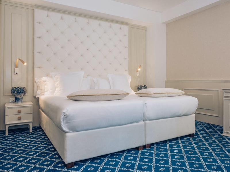 Elegantes Hotelzimmer mit komfortablem Doppelbett und blauem gemustertem Teppichboden.