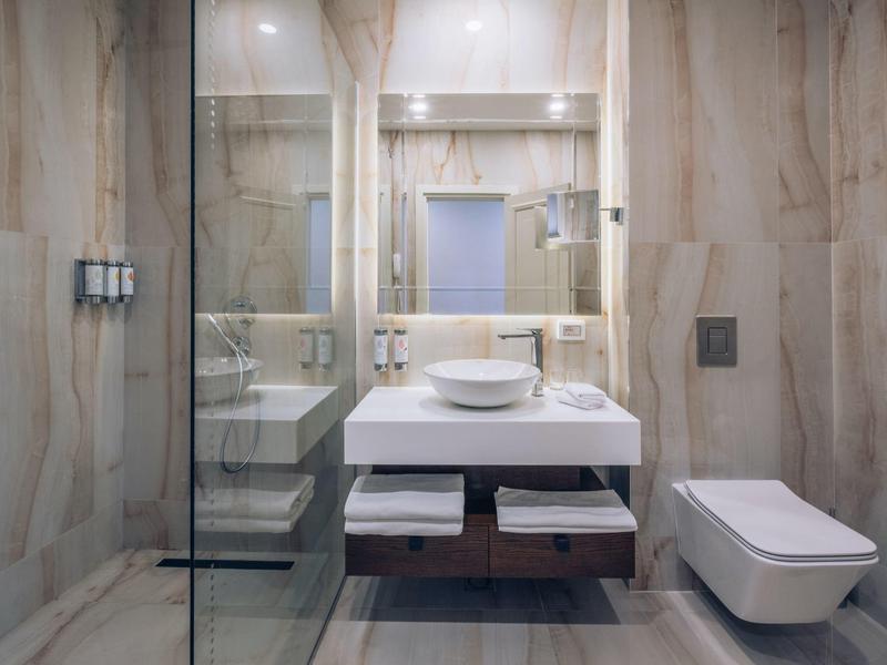 Modernes Badezimmer mit Waschbecken auf Holzunterschrank und Toilette neben Marmorboden