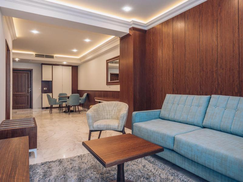 Modernes Wohnzimmer mit blauer Couch, Sesseln und Holzverkleidung in einem Hotelzimmer.