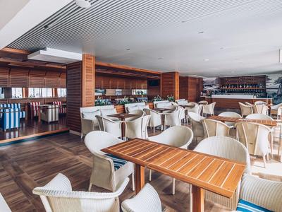 Jasna restauracja z drewnianymi stołami i białymi krzesłami w stylowym wnętrzu.