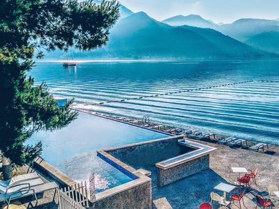 Jezioro górskie z basenem, tarasem i krzesłami, otoczone zalesionymi wzgórzami pod czystym niebem.