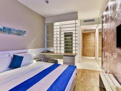 Nowoczesny pokój hotelowy z białym łóżkiem i niebieskimi akcentami oraz stylowym wystrojem.