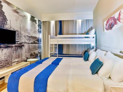 Nowoczesny pokój hotelowy z łóżkiem piętrowym, podwójnym łóżkiem, telewizorem i ścianą z widokiem na rzekę