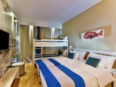 Pokój hotelowy z podwójnym łóżkiem, łóżkami piętrowymi i nowoczesnym wystrojem.