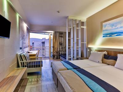 Nowoczesny pokój hotelowy z podwójnym łóżkiem, częścią wypoczynkową, balkonem i widokiem na morze