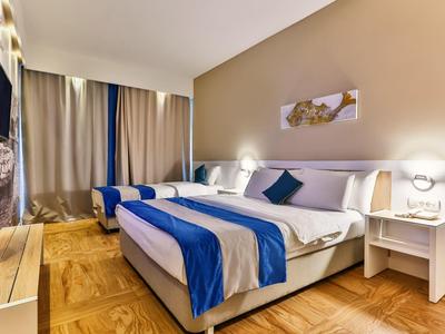 Nowoczesny pokój hotelowy z łóżkiem podwójnym, niebieskimi akcentami i drewnianą podłogą.