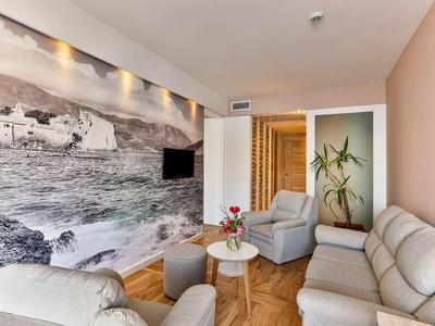 Nowoczesny salon z szarą sofą, fotelami i dużym muralem przedstawiającym morze.