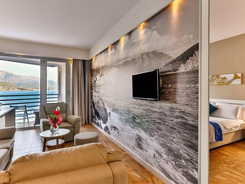 Nowoczesne lobby hotelowe z widokiem na jezioro i góry przez duże okna.