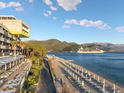 Hotelterrasse und Poolbereich mit Blick auf Meer und Kreuzfahrtschiff vor Bergen.