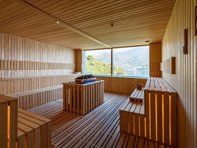 Moderner Saunaraum mit hellem Holz, großen Fenstern und Blick auf die Berge.