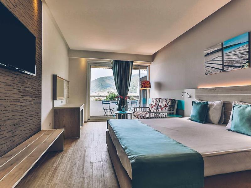 Modern hotel room with large bed, seating area, and mountain view