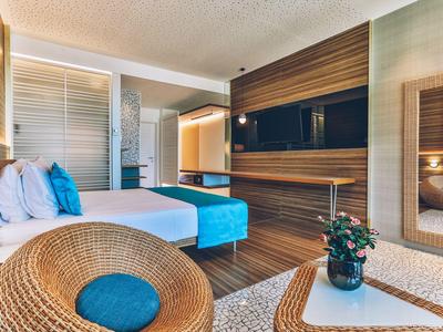 Modern hotel room with double bed, wood paneling, and cozy seating area.