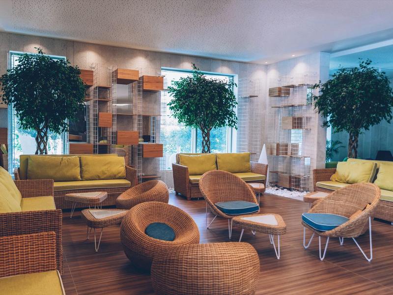 Cozy hotel lounge area with modern seating and large plants.
