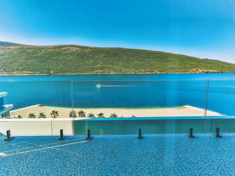 View of a terrace with pool and sea in front of a green peninsula