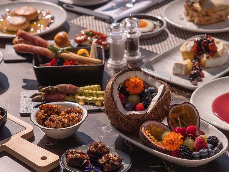 Vielseitiges Buffet mit kleinen Snacks, Würstchen, Dips und Desserts auf gedecktem Tisch.