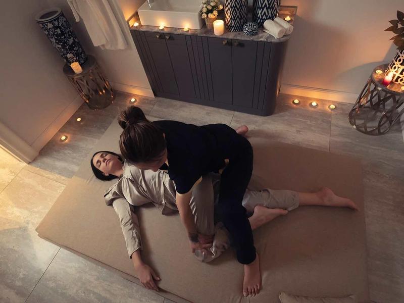 Zwei Personen liegen entspannt auf einer Matte im warm beleuchteten, gemütlichen Raum.