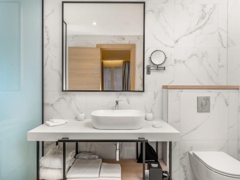 Salle de bain d'hôtel moderne avec lavabo, miroir et toilettes aux couleurs claires.