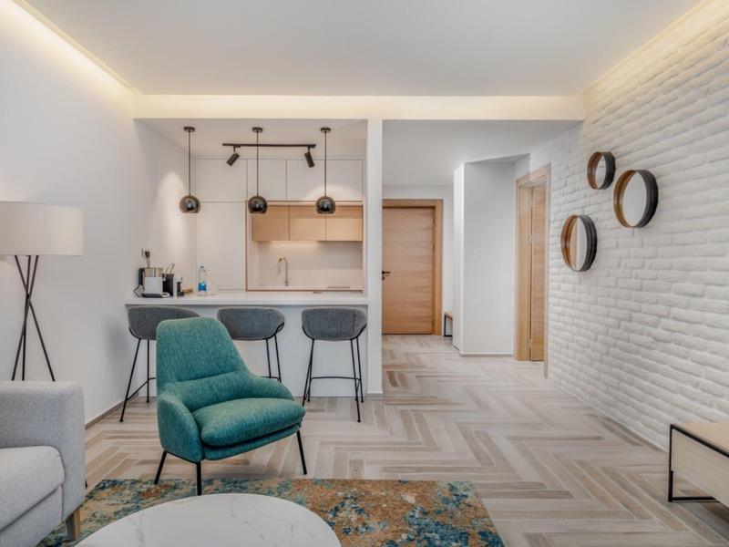 Salon moderne avec fauteuil confortable, îlot de cuisine et éclairage élégant.