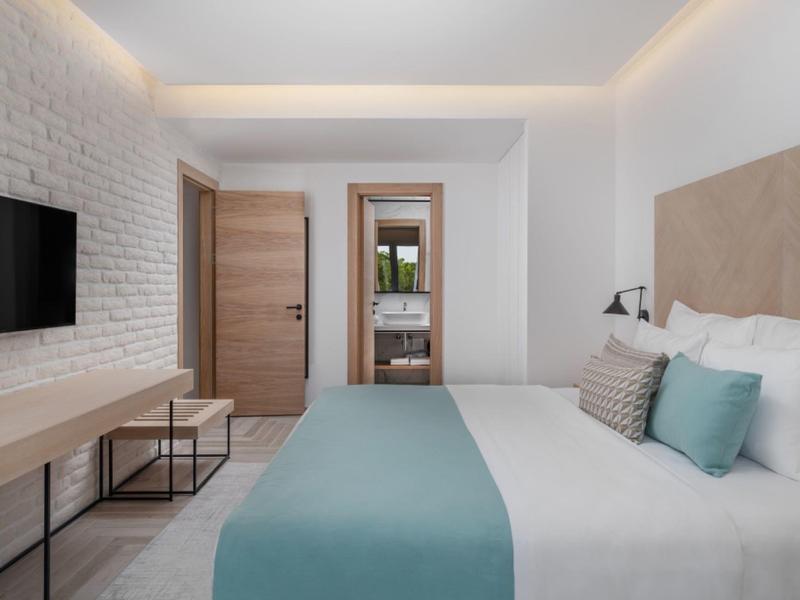 Chambre d'hôtel moderne avec lit double, télévision murale et vue sur la salle de bain.