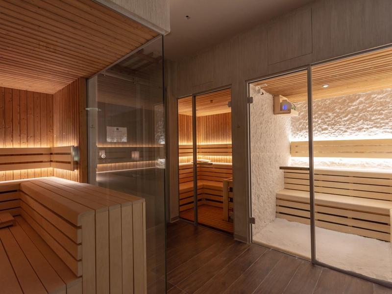Sauna moderne avec bancs en bois et parois vitrées dans un espace bien-être.