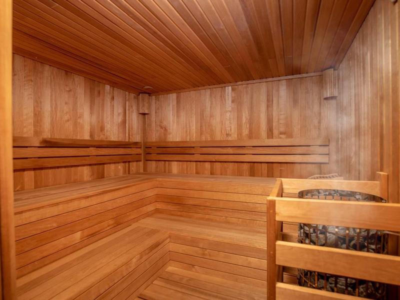 Holzsauna mit hölzernen Sitzbänken und einem Saunaofen mit Steinen in der Ecke.