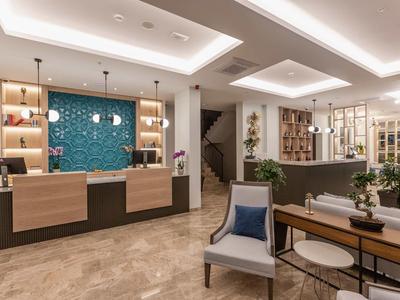 Hall d'hotel arredato modernamente con banco reception e aree salotto accoglienti.