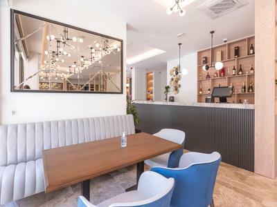 Zona pranzo moderna con tavolo in legno lungo, divano grigio e sedie blu.