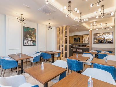 Sala da pranzo moderna con sedie blu e bianche e tavoli in legno in un ambiente luminoso.