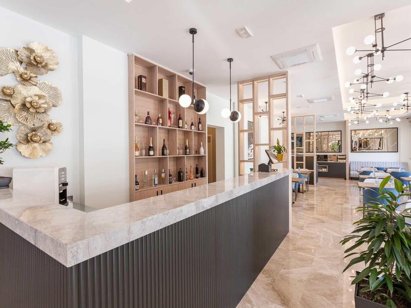 Moderner Eingangsbereich mit hellem Marmor-Tresen, Holzregalen, Pflanzen und schöner Beleuchtung.