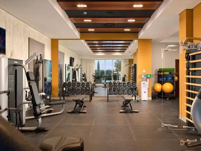 Moderner Fitnessraum mit verschiedenen Trainingsgeräten und Blick auf große Fenster.