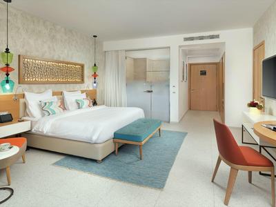 Modernes Hotelzimmer mit großem Bett, Schreibtisch, Stuhl und stilvoller Dekoration.